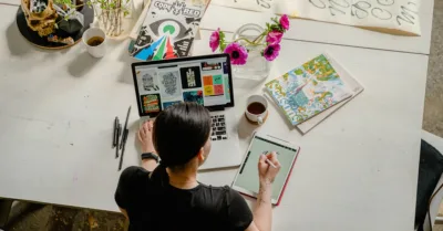 Photo of Woman Writing on Tablet Computer While Using Laptop